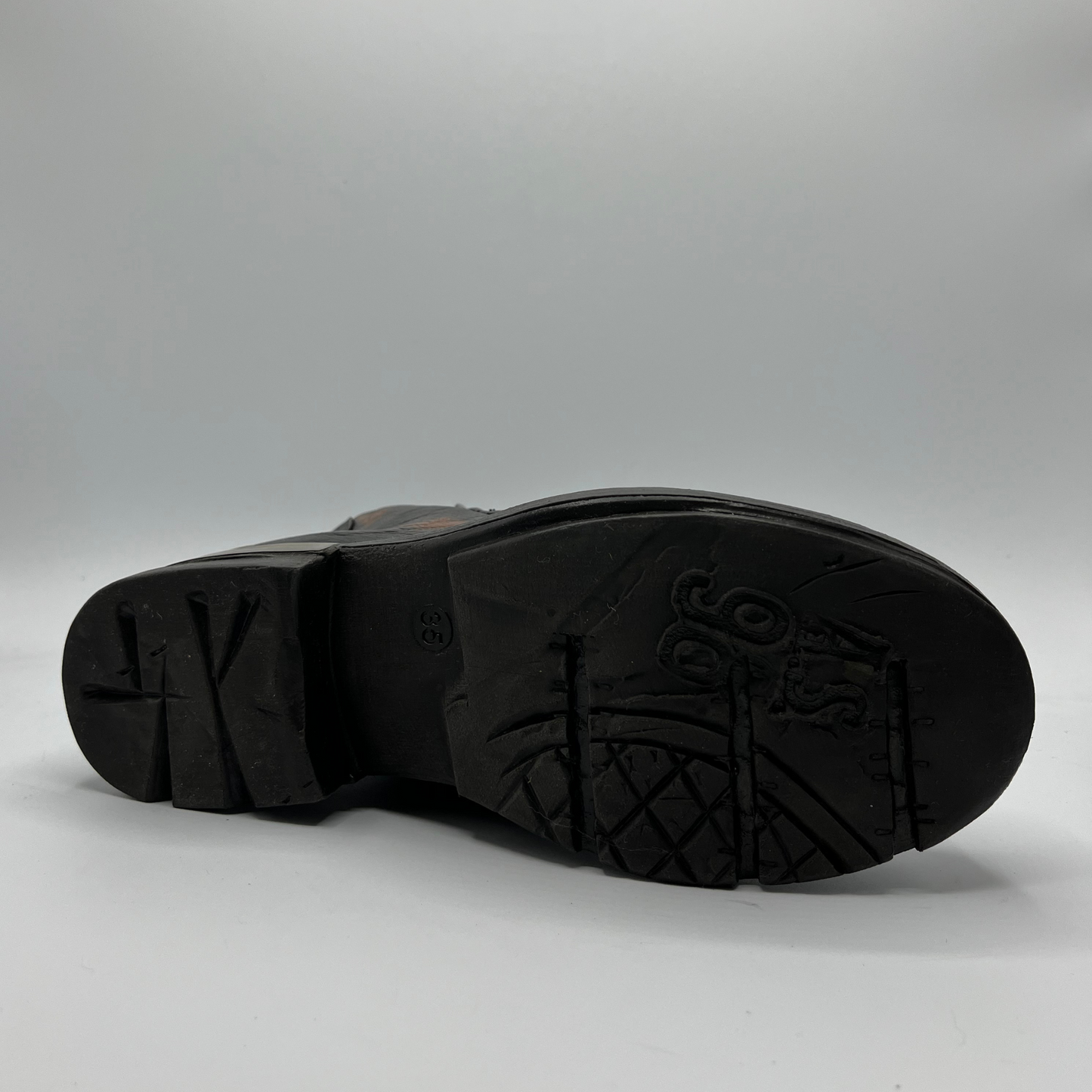 Bottom view of a brown and black burnished short boot with a gold accent on the heel and metallic embellishments along the shaft.