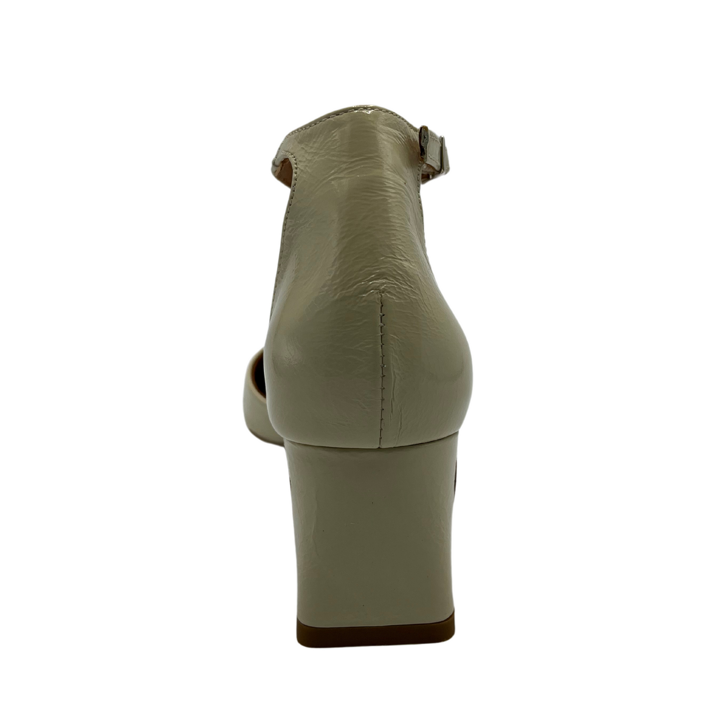 Back view of a patent leather pump in off white. Featuring a delicate ankle strap, rounded toe and flared block heel.