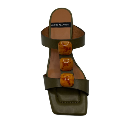 Top view of khaki leather sandal with square toe and square ornaments on upper. Flared heel and padded insole.
