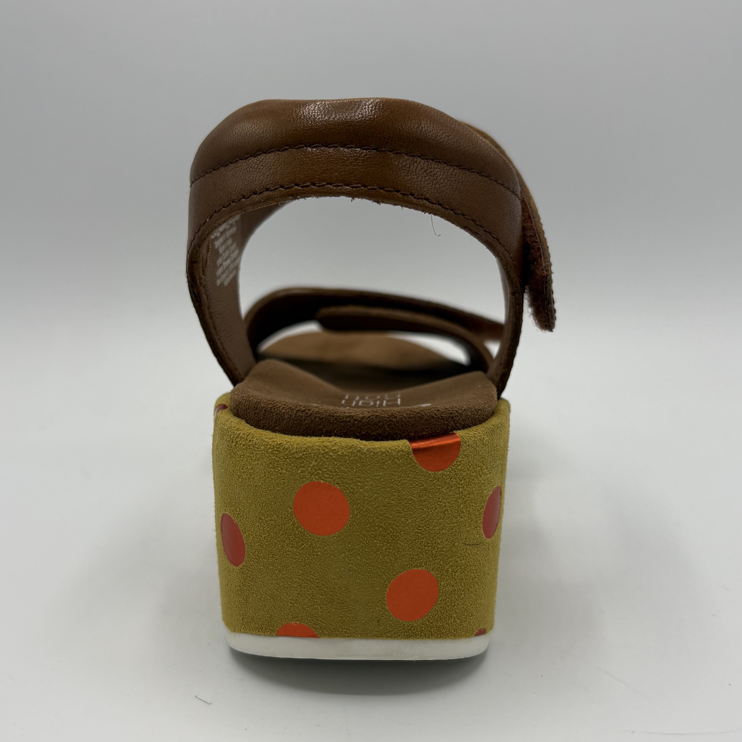 Brown sandal with a green sole featuring red polka dots on a gray background