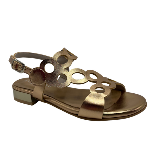 45 degree angled view of cut out leather sandal in metallic gold with a delicate ankle buckle strap and short block heel