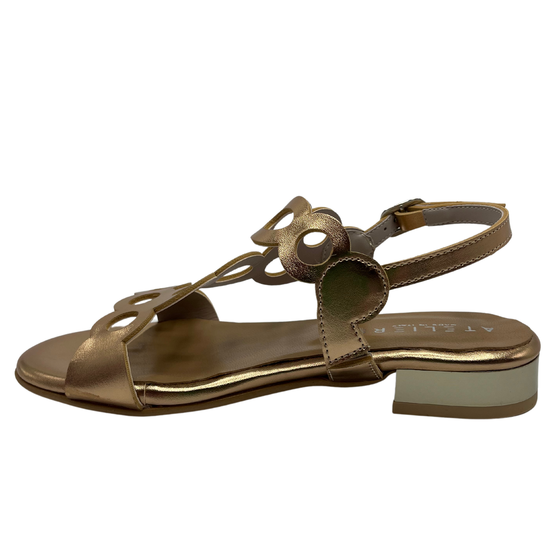 Left view of cut out leather sandal in metallic gold with a delicate ankle buckle strap and short block heel