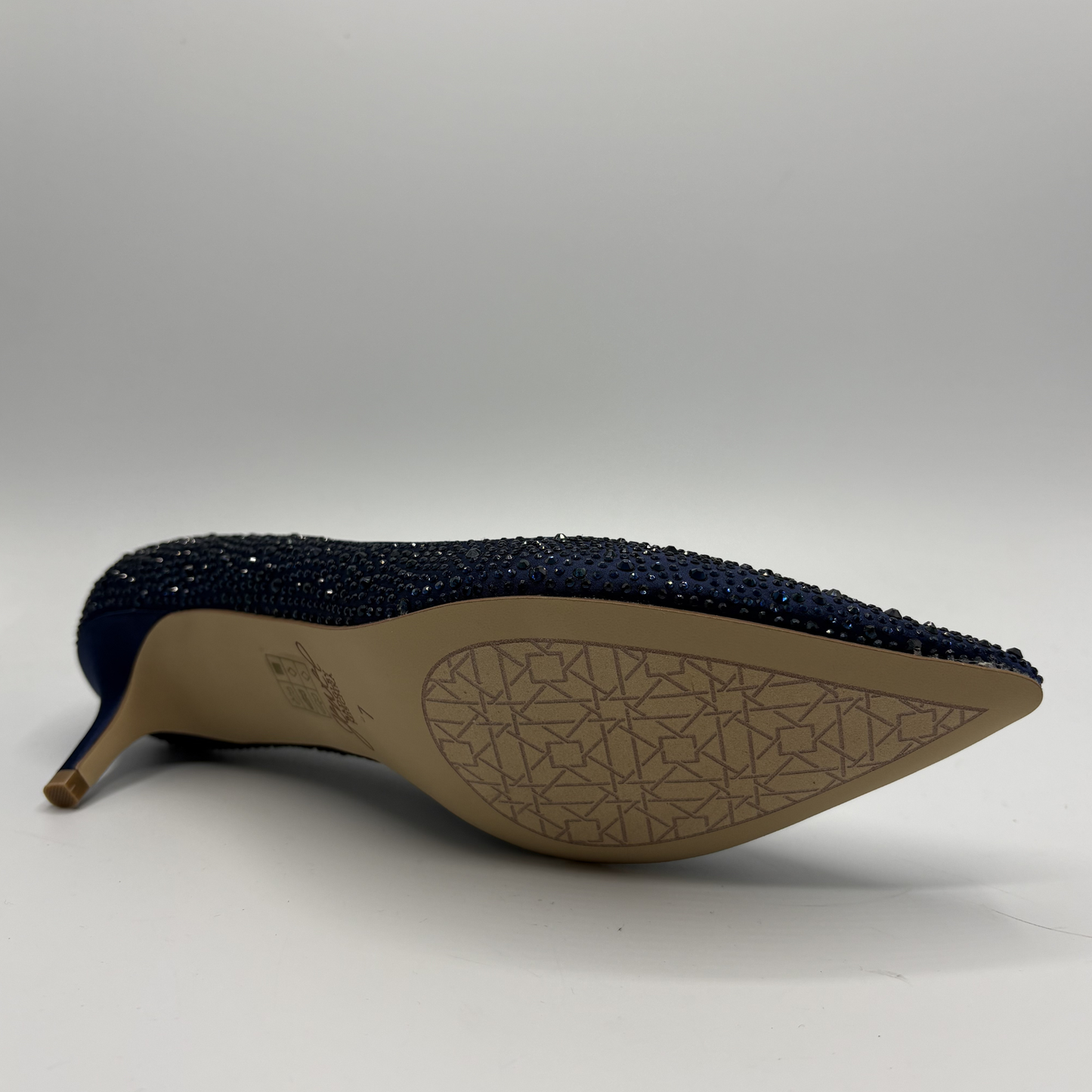 Navy blue high-heeled shoe with a patterned sole on a white background