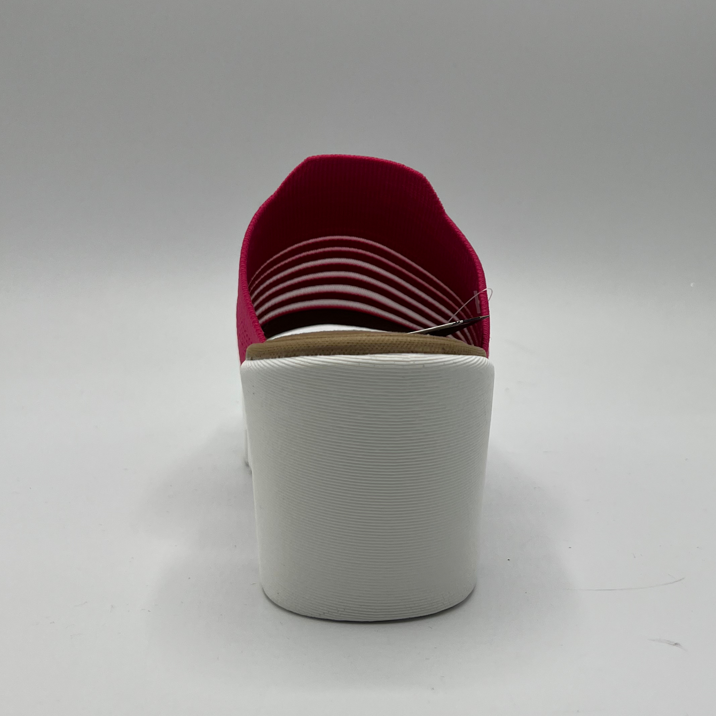 Back view of a fuschia elastic slip on sandal with a white wedge heel.