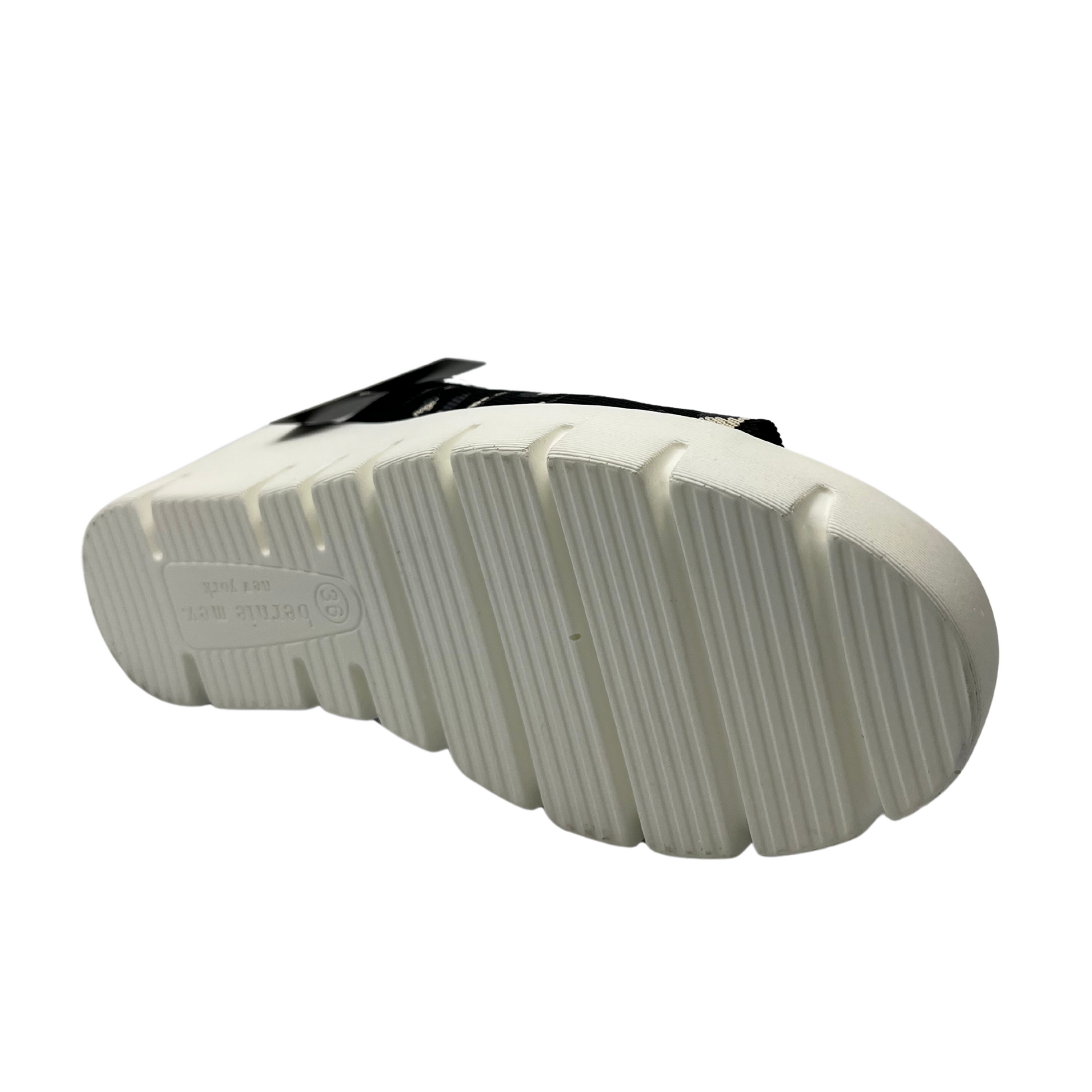 Bottom facing view of a slip on wedge heel. White rubber outsole and stretchy knit upper.