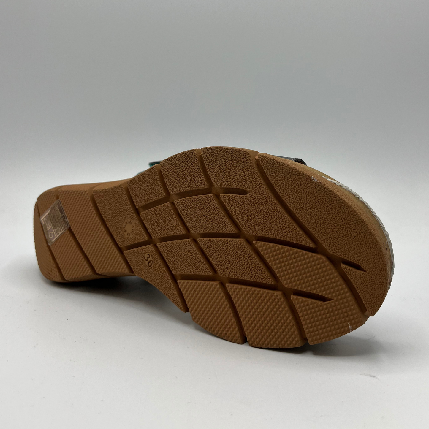 Bottom view of a leather sandal in shades of turquoise on the upper and an adjustable velcro strap and a thick wedge heel.
