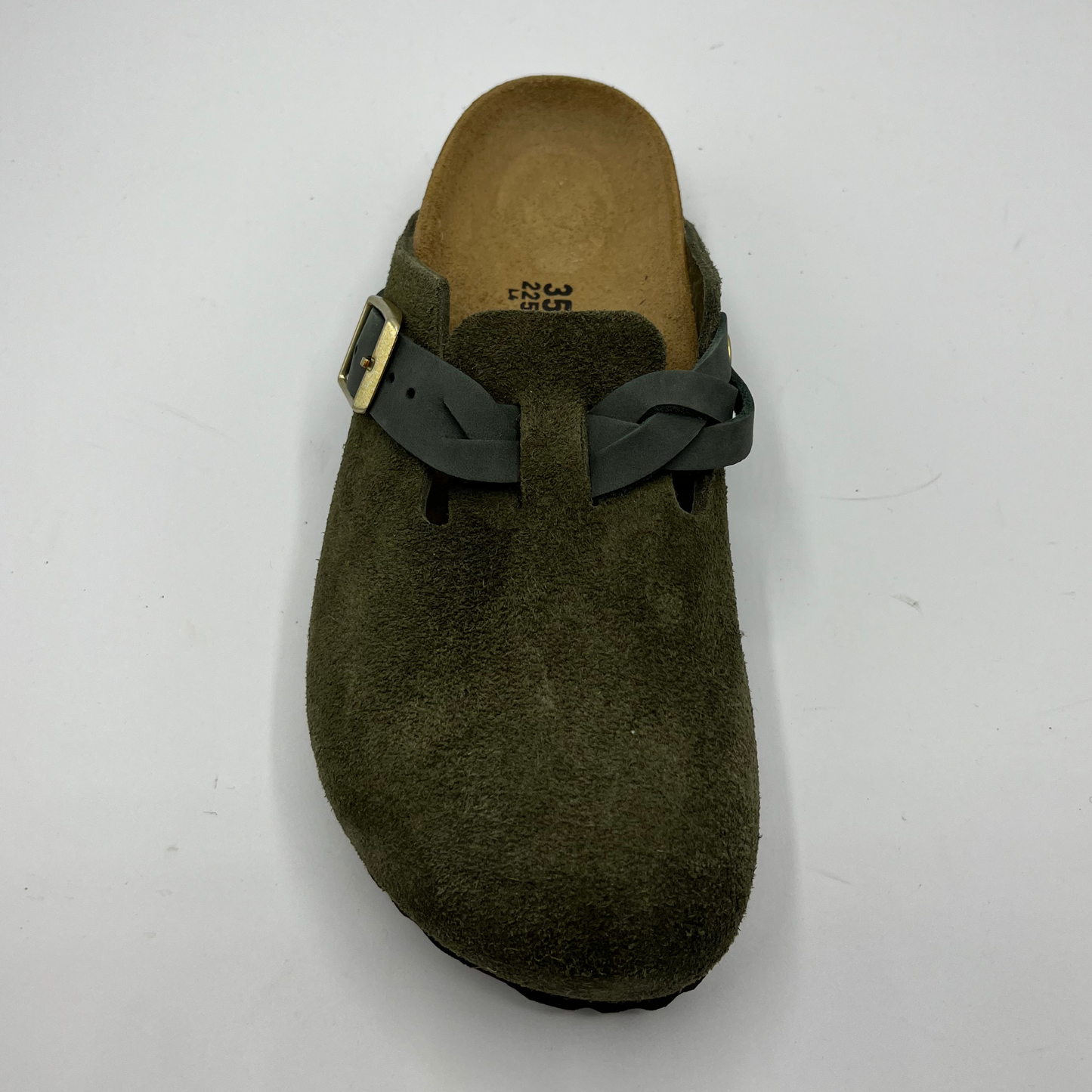 Green clog shoe with a strap on a white background
