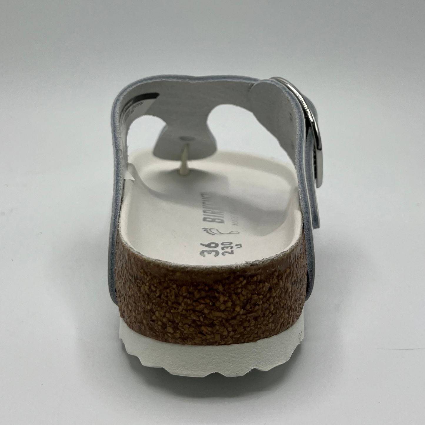 Back view of a white leather thong sandal with a big silver buckle on the adjustable strap. Featuring a contoured cork footbed with a leather lining.