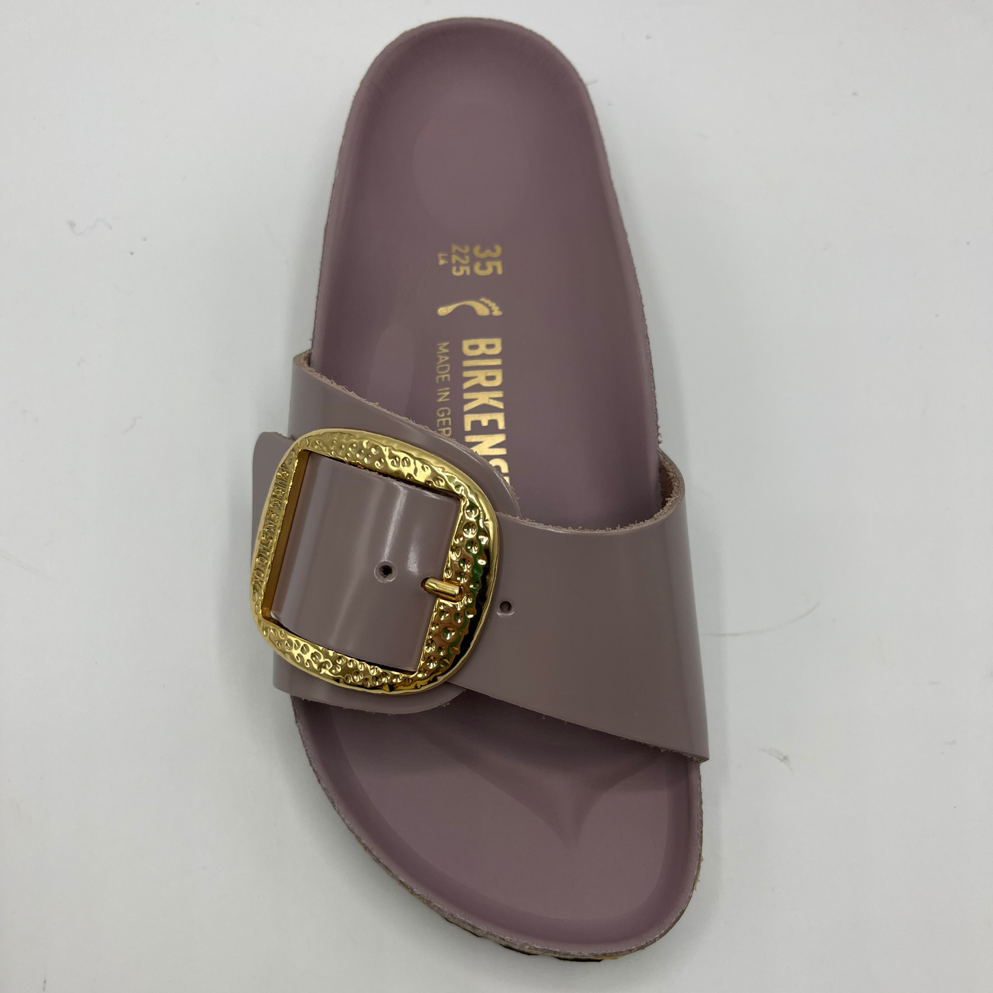 Top view of a faded purple slip on sandal with a big gold buckle on the strap. Featuring a lined, contoured cork footbed