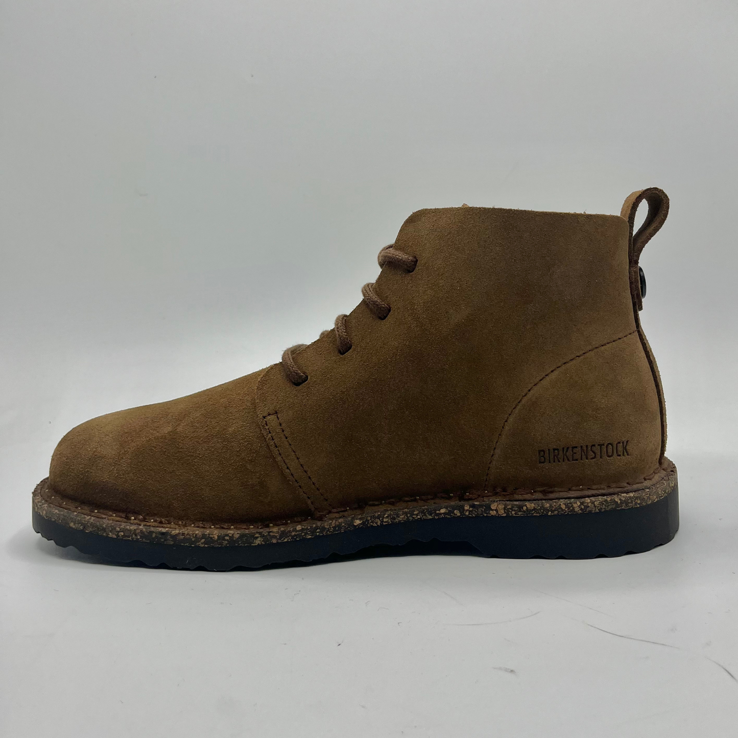 Brown suede boot with black sole on a white background
