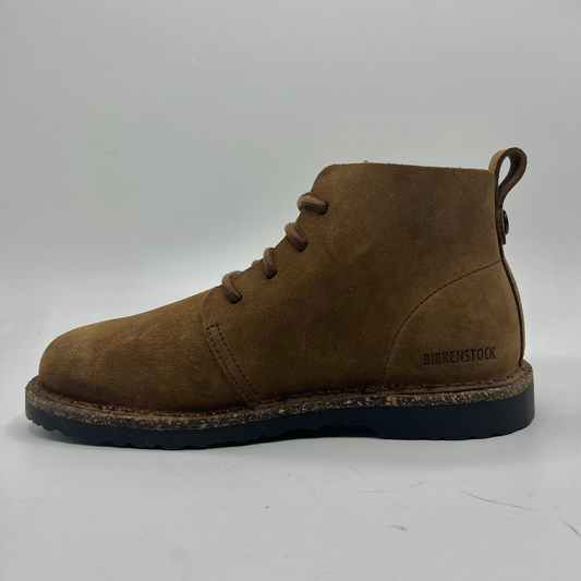 Brown suede boot with black sole on a white background