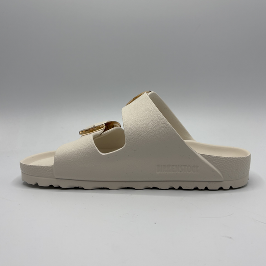 Eggshell sandal with a gold buckle on a white background