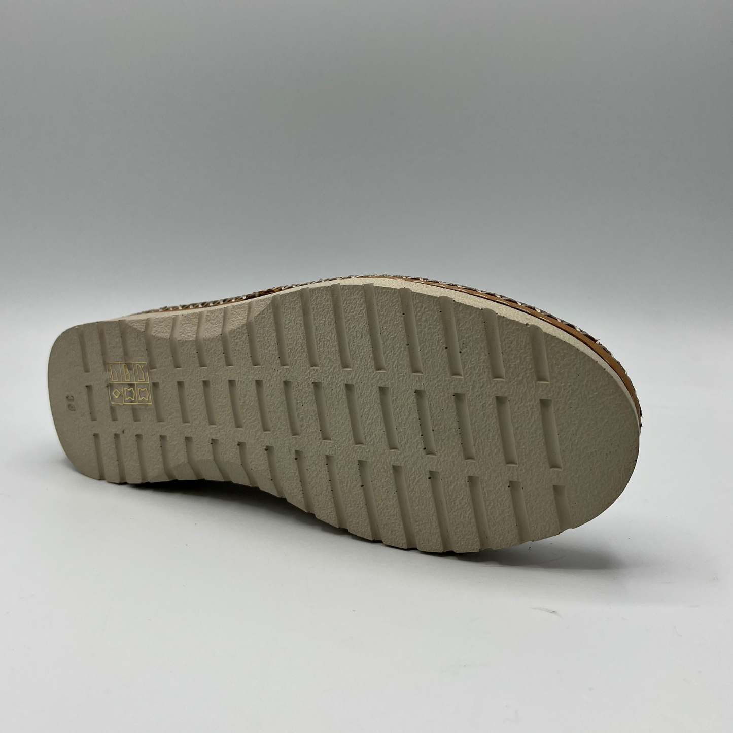 Bottom view of a leather slip on shoe with a laser cut design on the upper. Hand stitched details connecting the upper to the outsole. Pull on heel tab and leather lined.