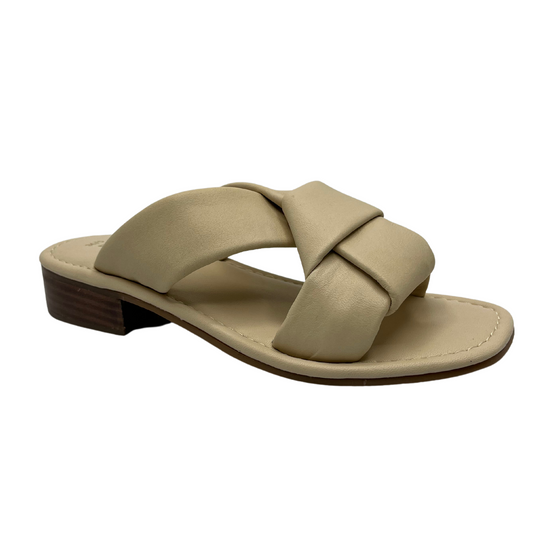 45 degree angled view of cream leather sandal with short block heel and large knot detail on straps.