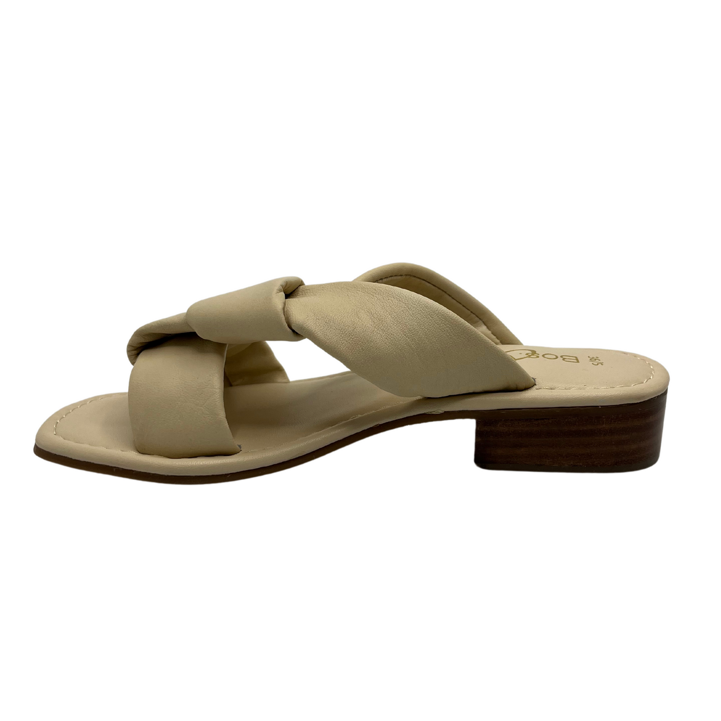 Left facing view of cream leather sandal with short block heel and large knot detail on straps.