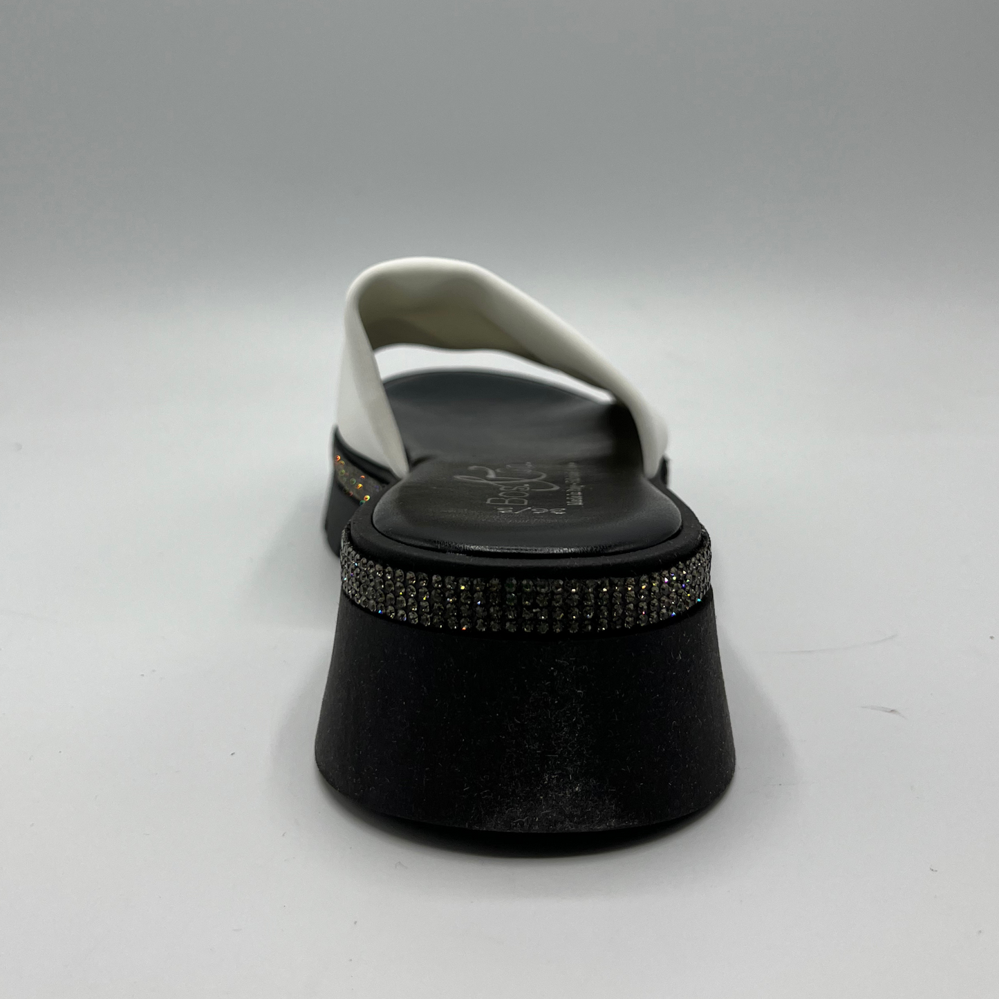 Back view of a black and white sandal with a white leather upper and a rhinestone wrap detail around the upper.
