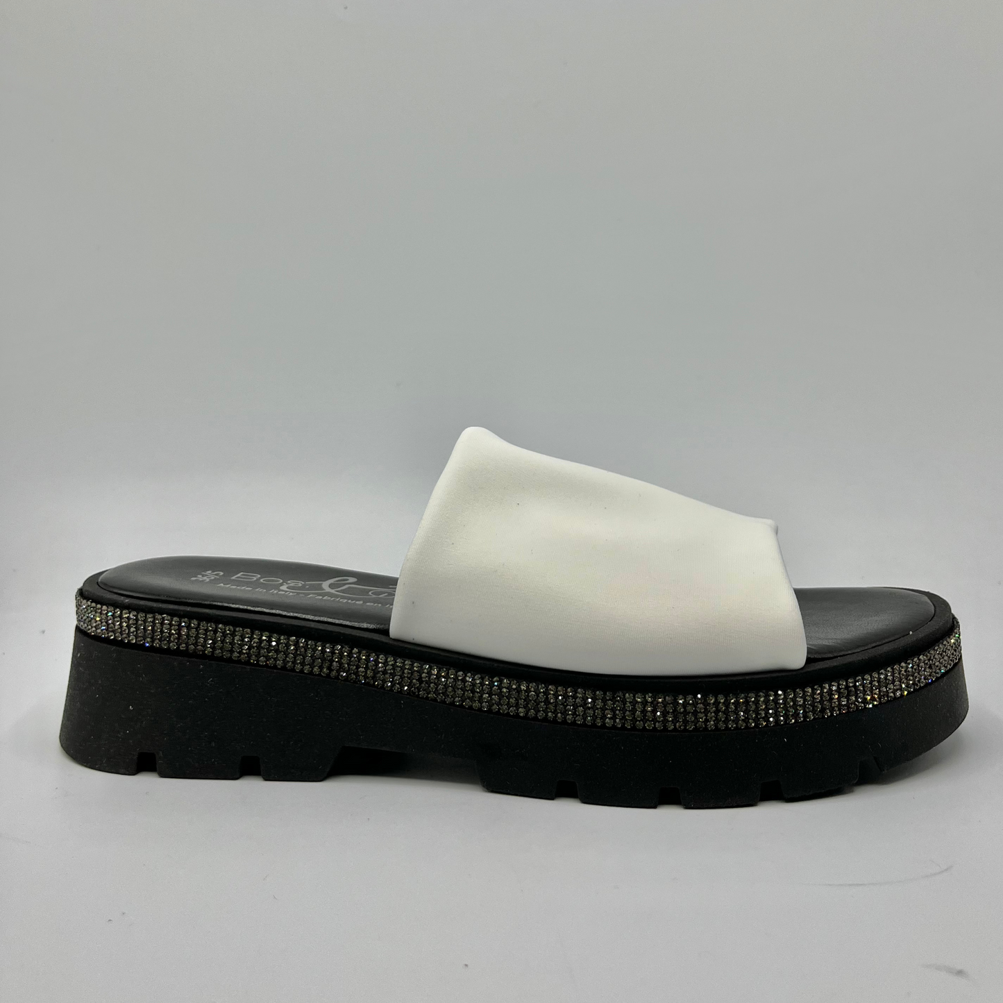 Right facing view of a black and white sandal with a white leather upper and a rhinestone wrap detail around the upper.