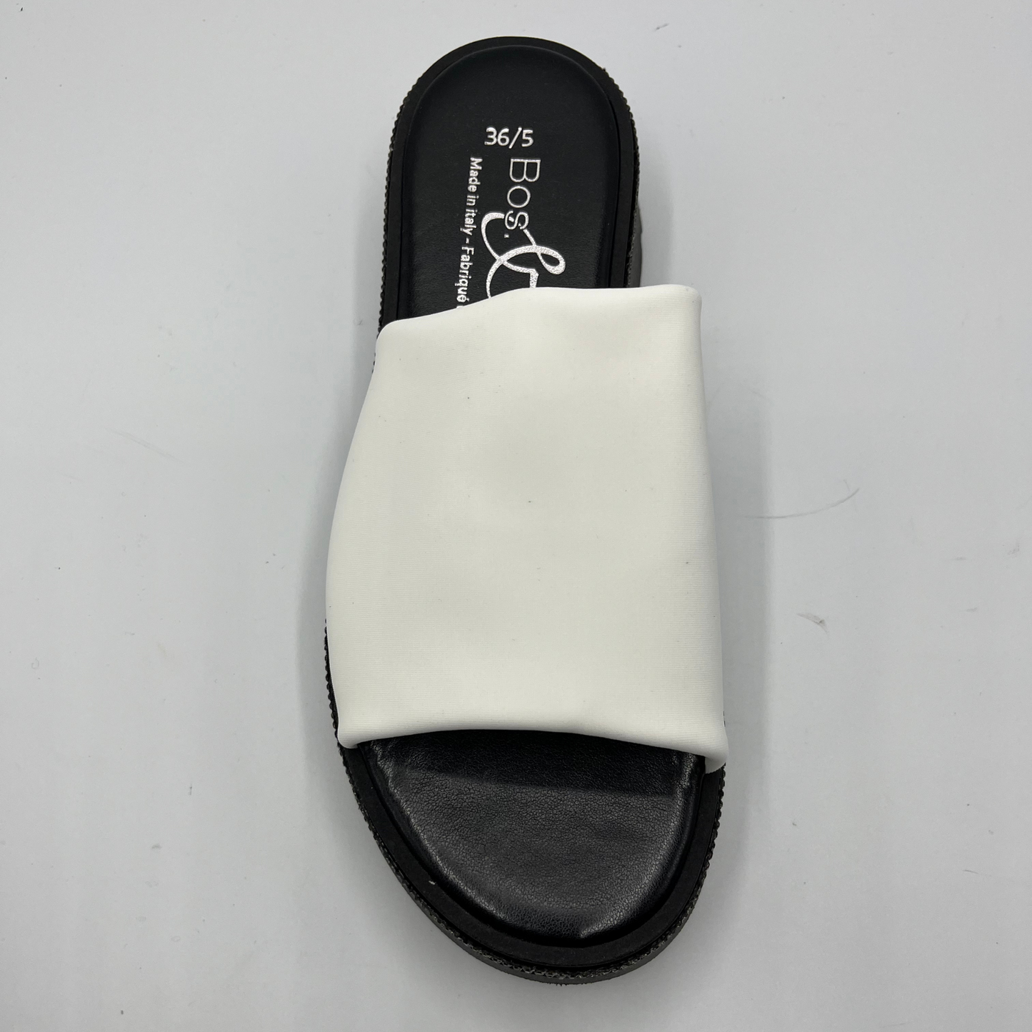 Top view of a black and white sandal with a white leather upper and a rhinestone wrap detail around the upper.