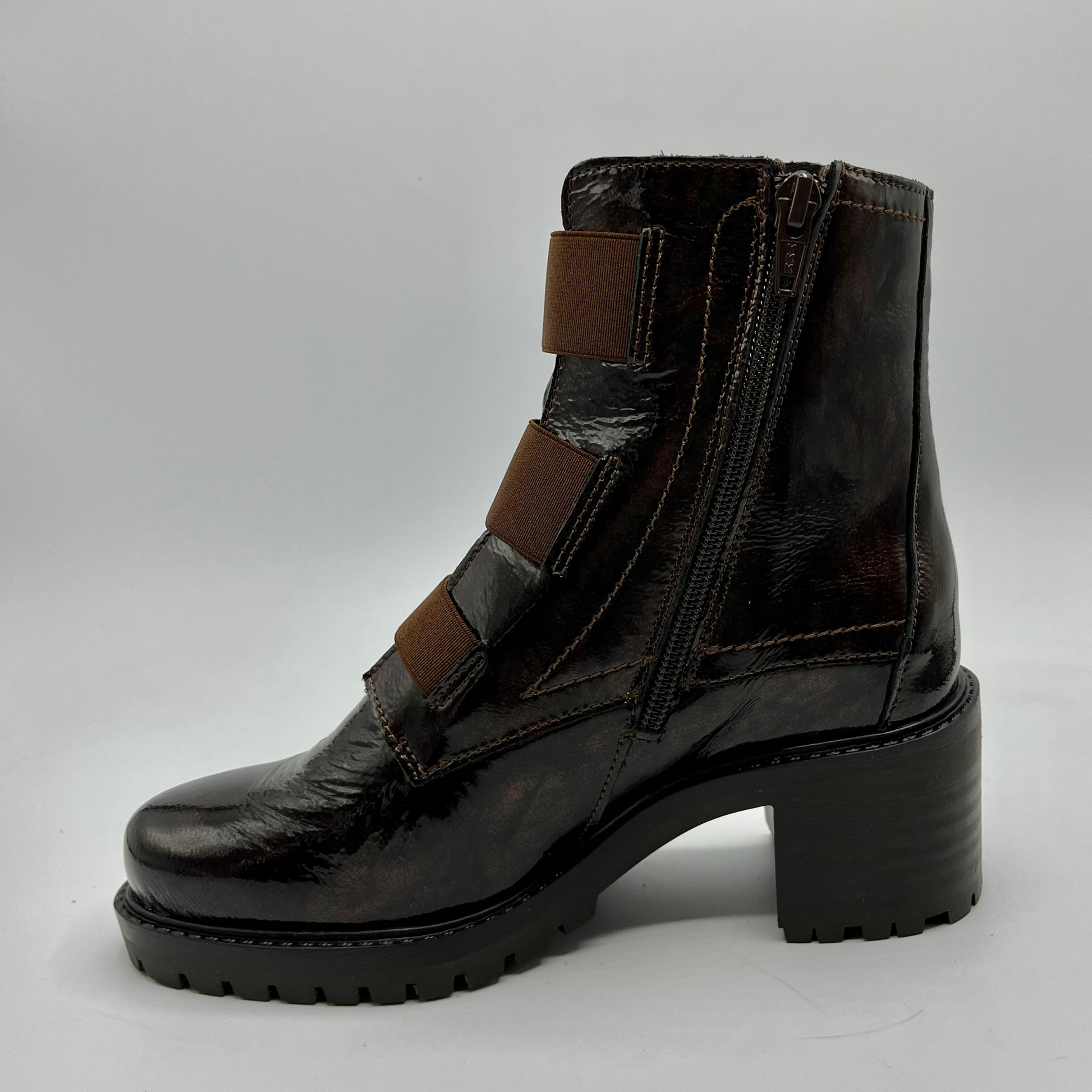 Black leather boot with brown straps on a gray background
