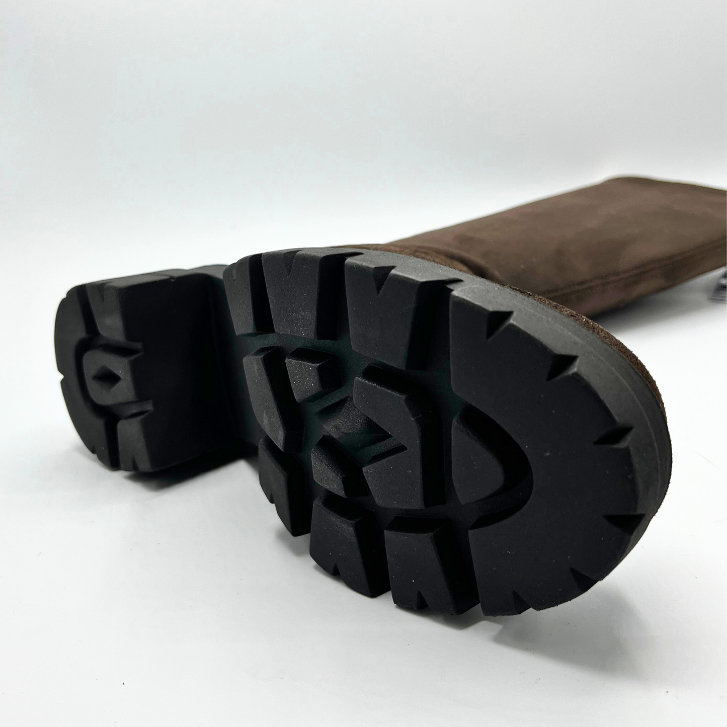 Close-up of brown leather boots with black soles on a white background