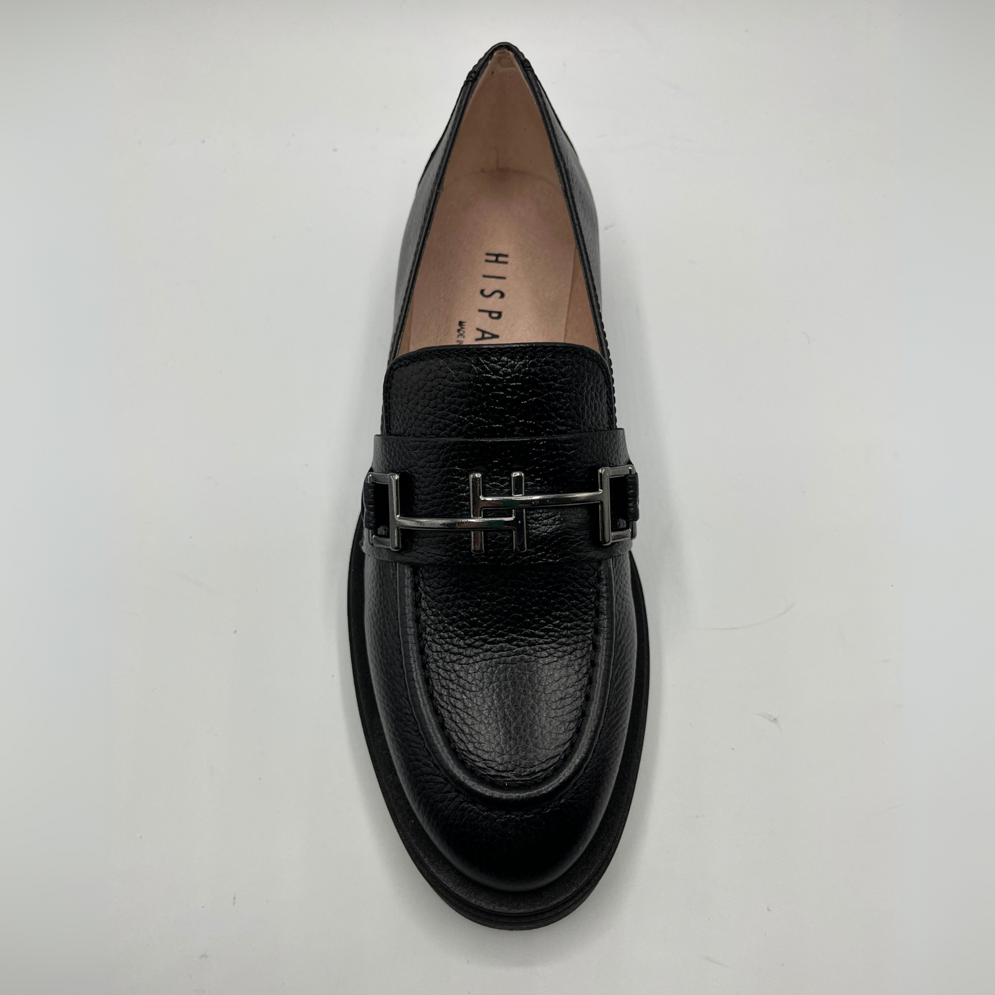 Black loafer shoe with a metallic buckle on a white background