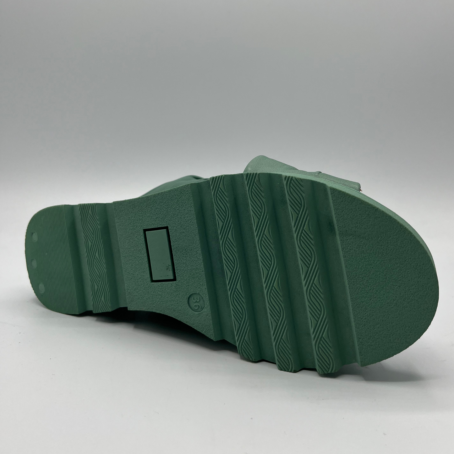 Bottom view of a leather slip on sandal in seafoam. Rouched cross strapped design and a wedge heel.