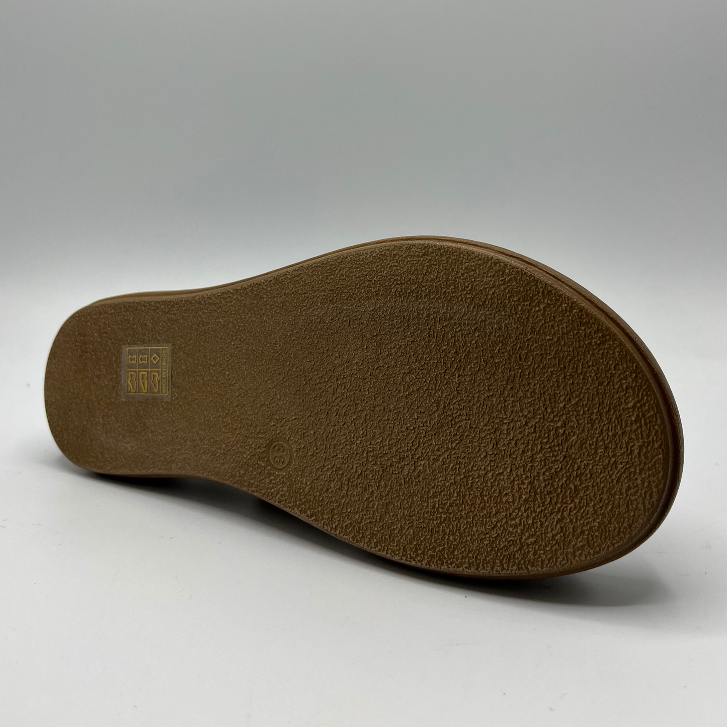 Bottom view of a mustard coloured suede sandal with a thick platform sole and an adjustable slingback strap.