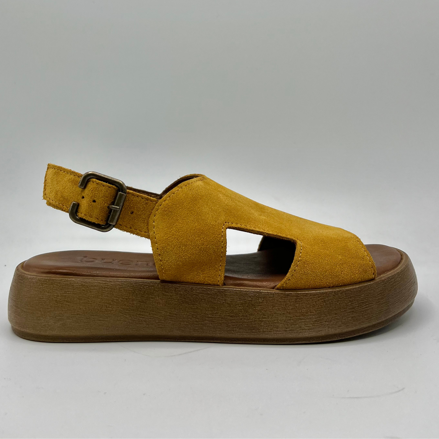 Right facing view of a mustard coloured suede sandal with a thick platform sole and an adjustable slingback strap.