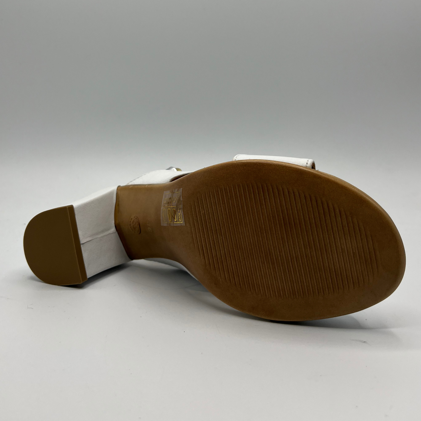 Bottom view of leather sandal with white straps. It has a block heel and a silver slingback strap