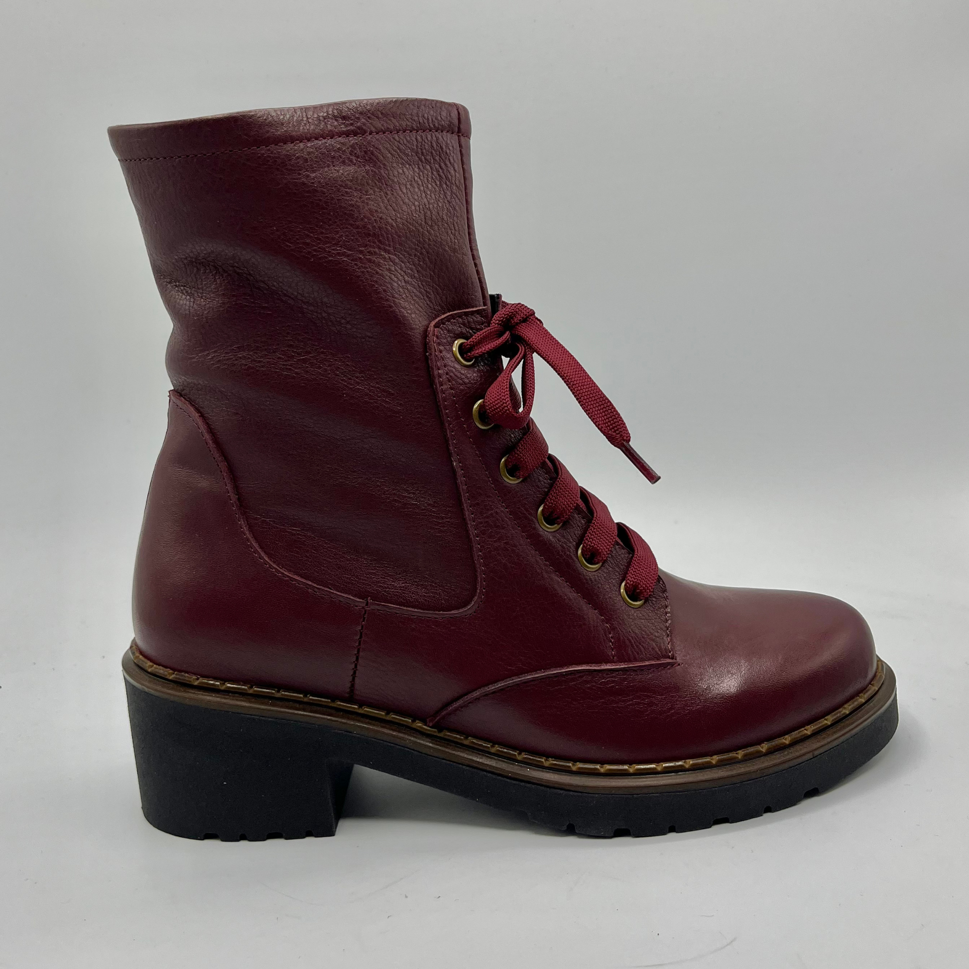 Maroon leather boot with a black sole on a light gray background