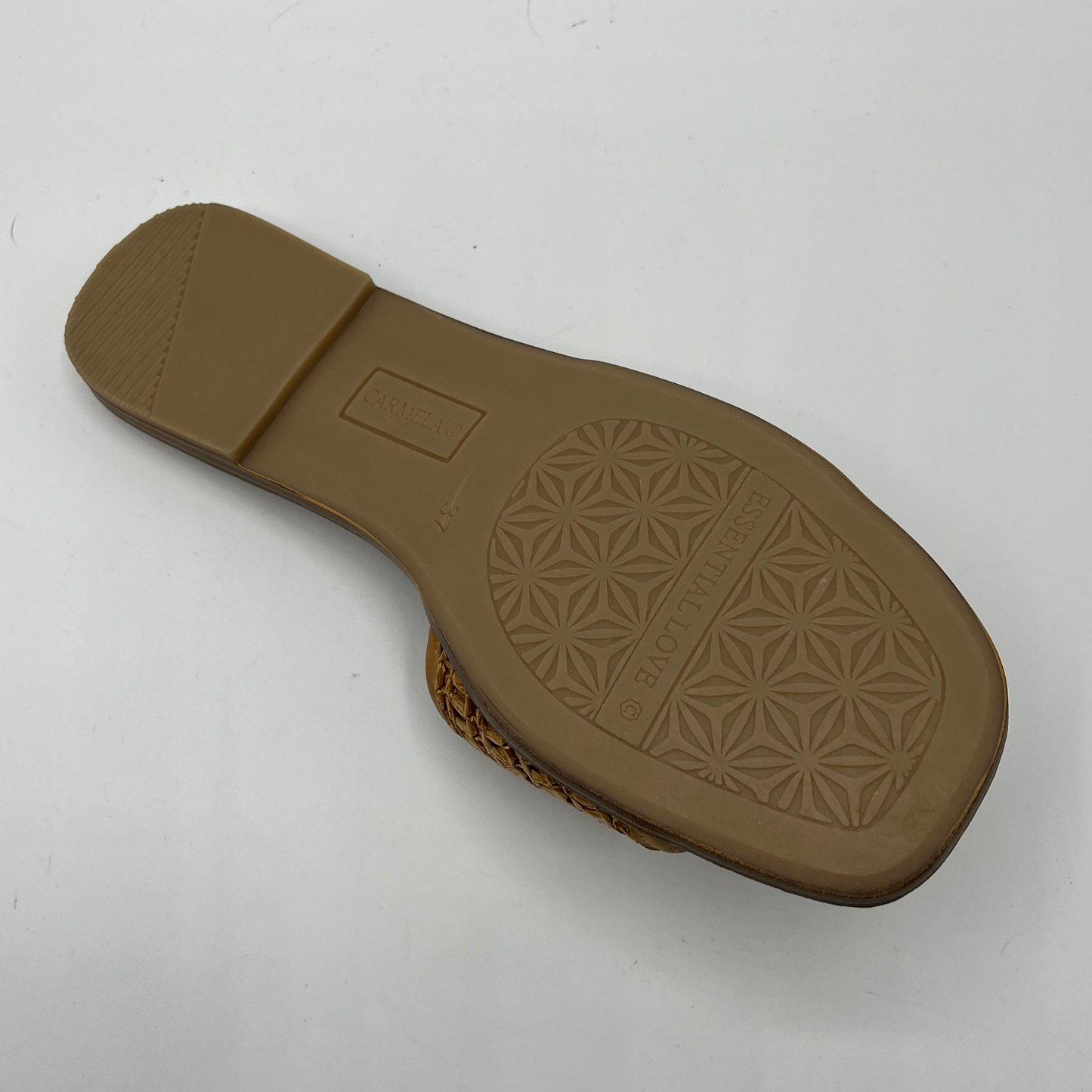 Bottom view of a flat leather lined sandal with a chain pattern on the strap as well as decorative branding.