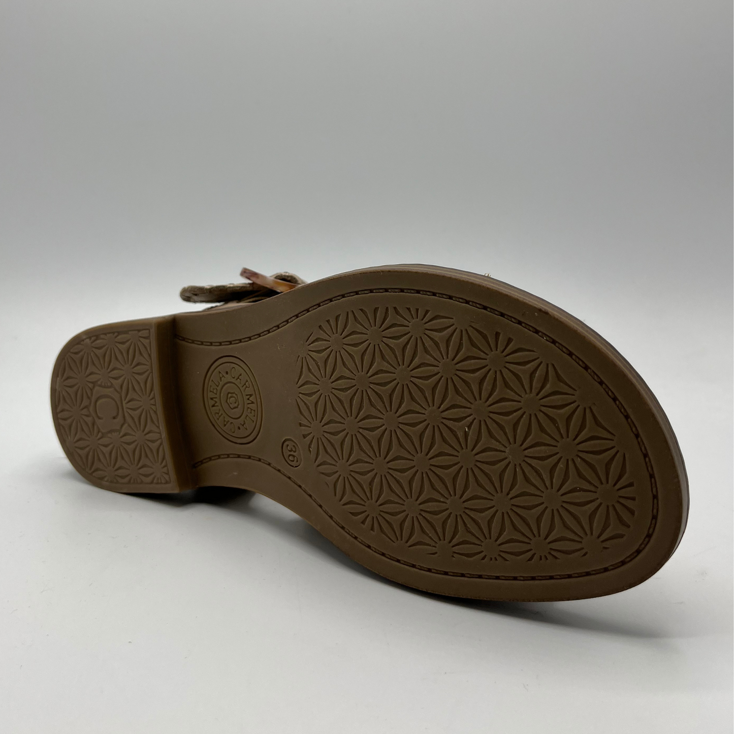 Bottom view of a leather sandal with a cushioned footbed and an adjustable strap with a tortoise shell buckle.