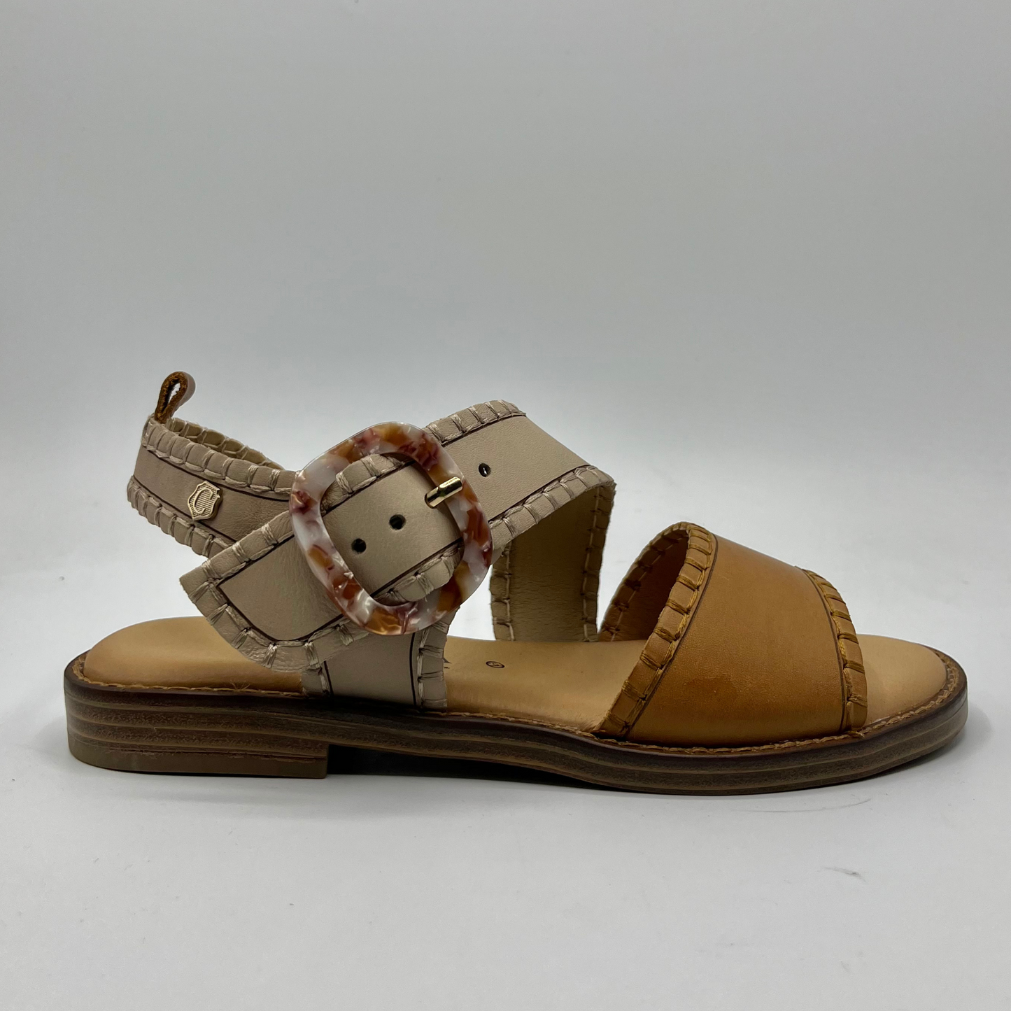 Right facing view of a leather sandal with a cushioned footbed and an adjustable strap with a tortoise shell buckle.