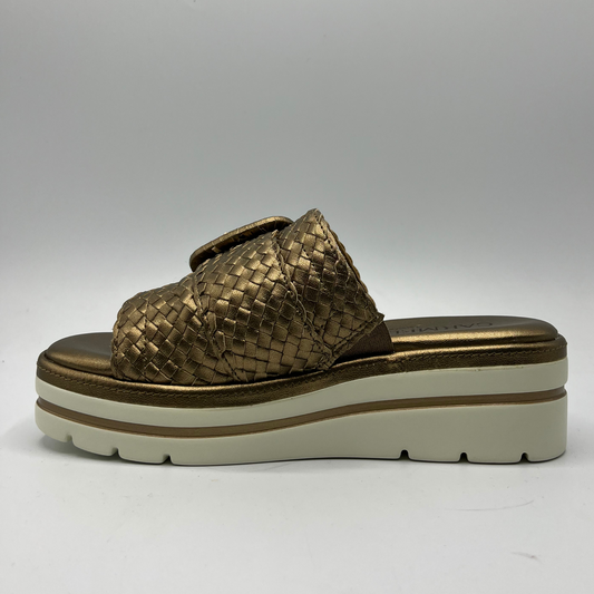 Left facing view of a bronze leather sandal with a white rubber outsole. Featuring a weave design on the strap and a decorative buckle.