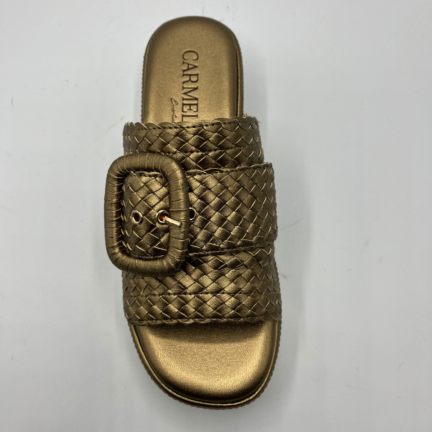 Top view of a bronze leather sandal with a white rubber outsole. Featuring a weave design on the strap and a decorative buckle.