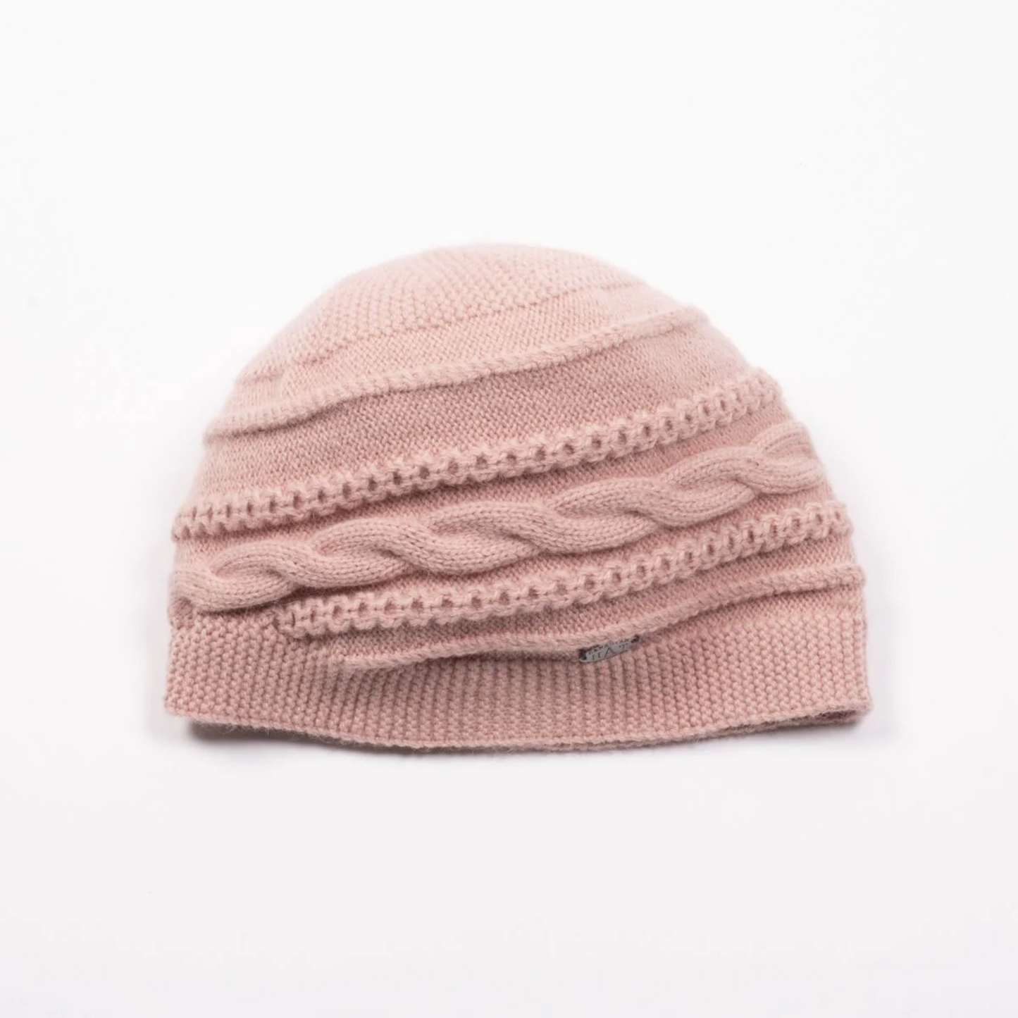 Front view of a round cable knit beanie in a soft pink colour.
