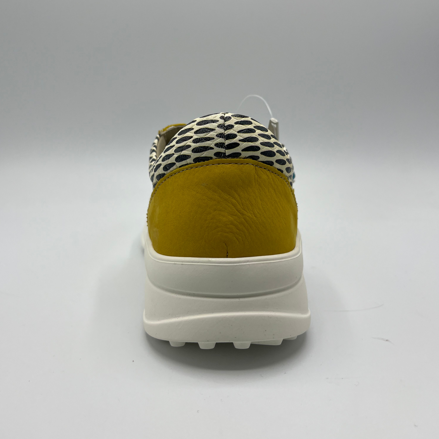 Back view of a mustard, black and white leather sneaker with a side zipper entry as well as functional laces. Removable insoles and 1.25 inch white rubber outsole.