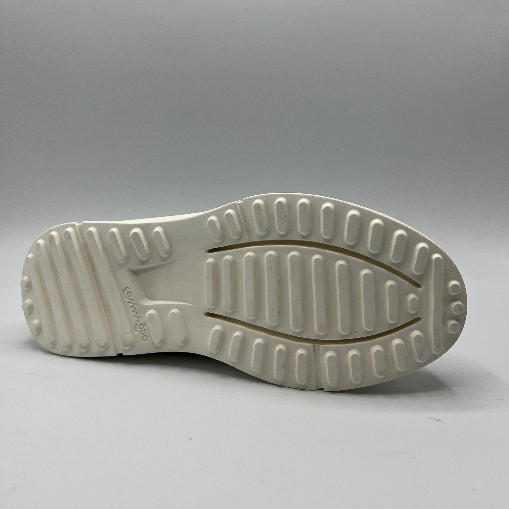 Bottom view of a mustard, black and white leather sneaker with a side zipper entry as well as functional laces. Removable insoles and 1.25 inch white rubber outsole.