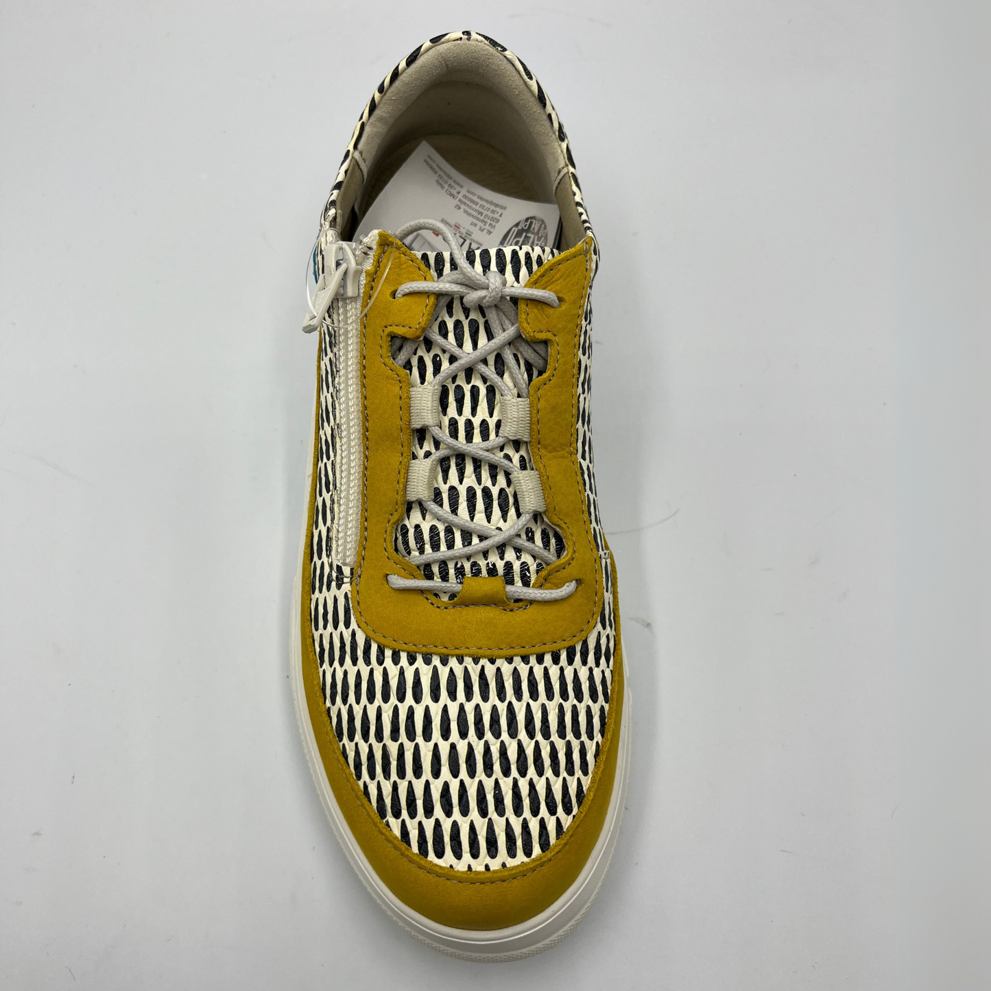 Top view of a mustard, black and white leather sneaker with a side zipper entry as well as functional laces. Removable insoles and 1.25 inch white rubber outsole.