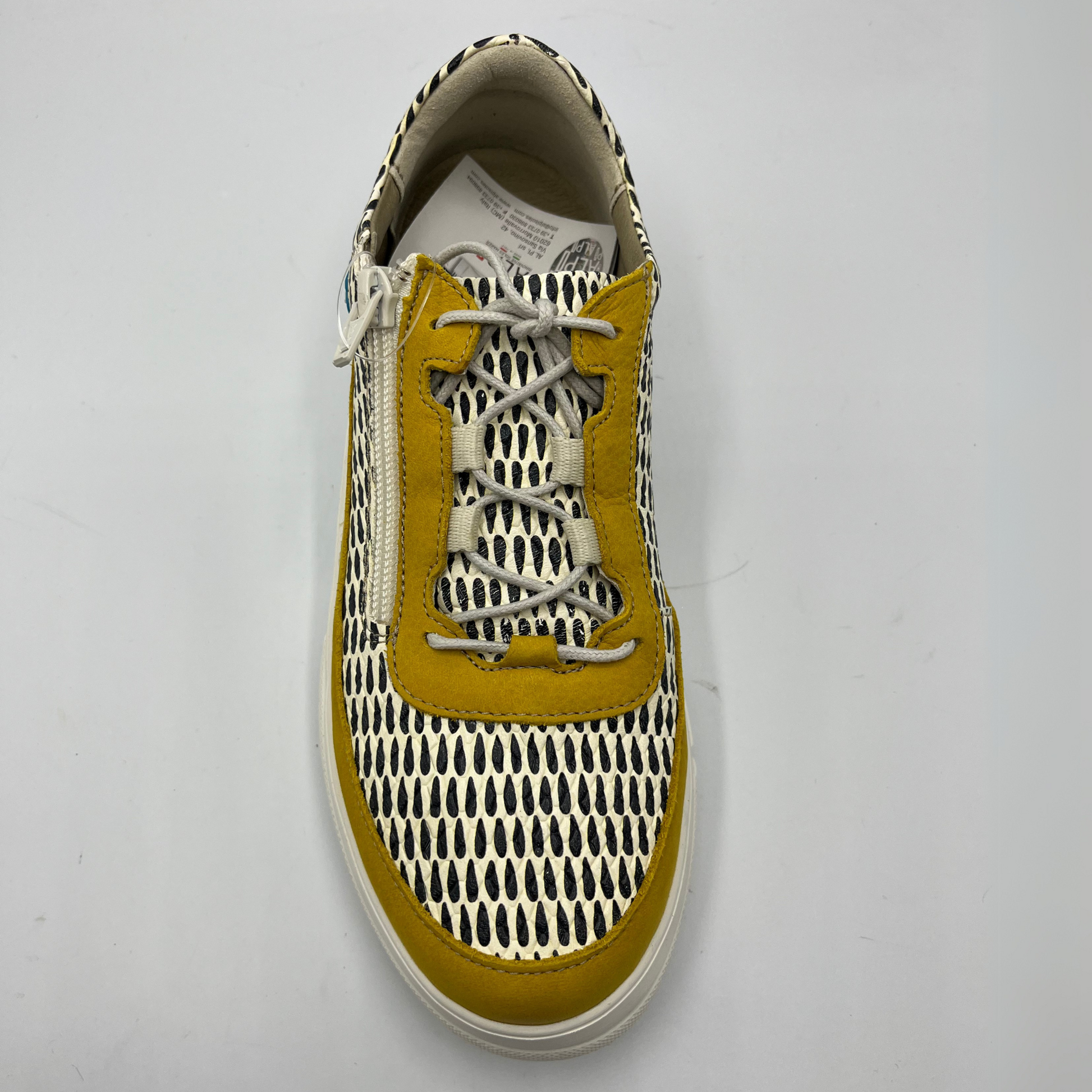 Top view of a mustard, black and white leather sneaker with a side zipper entry as well as functional laces. Removable insoles and 1.25 inch white rubber outsole.