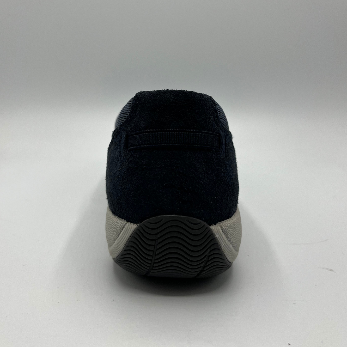 Black slip-on shoe with a gray sole on a white background