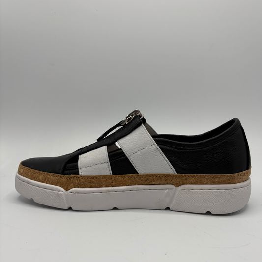 Black and white sneaker with a brown sole on a gray background