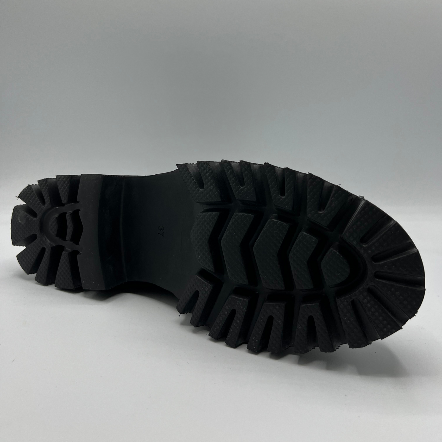 Close-up of a black boot sole on a gray background