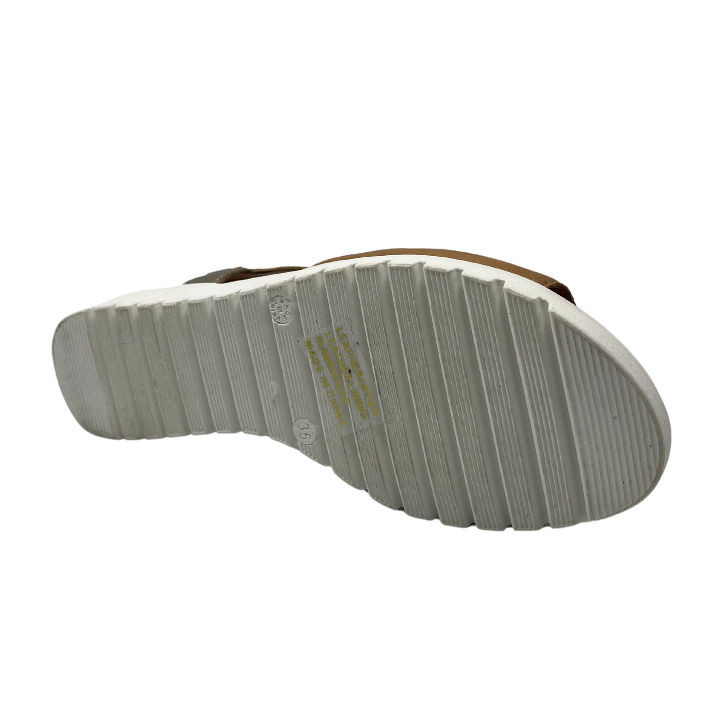 Bottom view of brown leather sandal with white low wedge heel