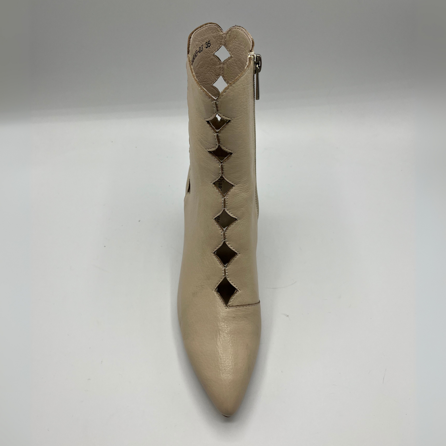 Beige shoe with decorative cut-out design on a white background
