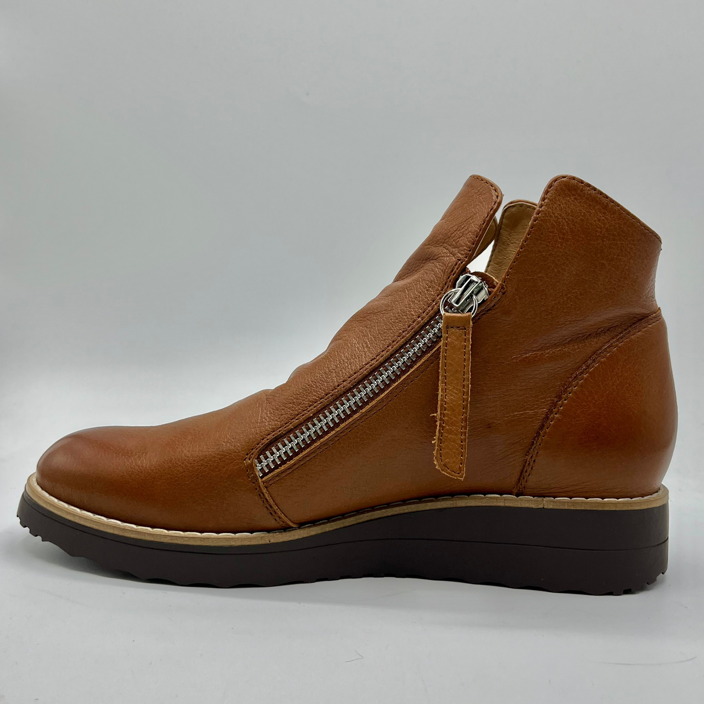 Brown leather ankle boot with a zipper on a gray background