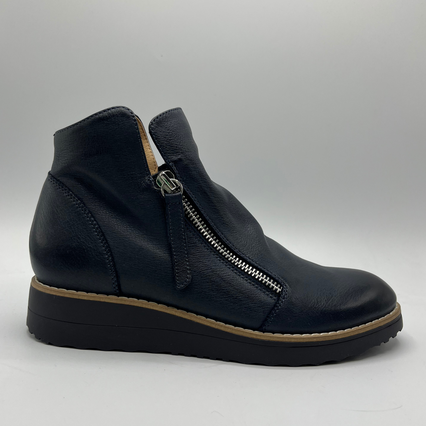 Navy ankle boot with a zipper on a gray background