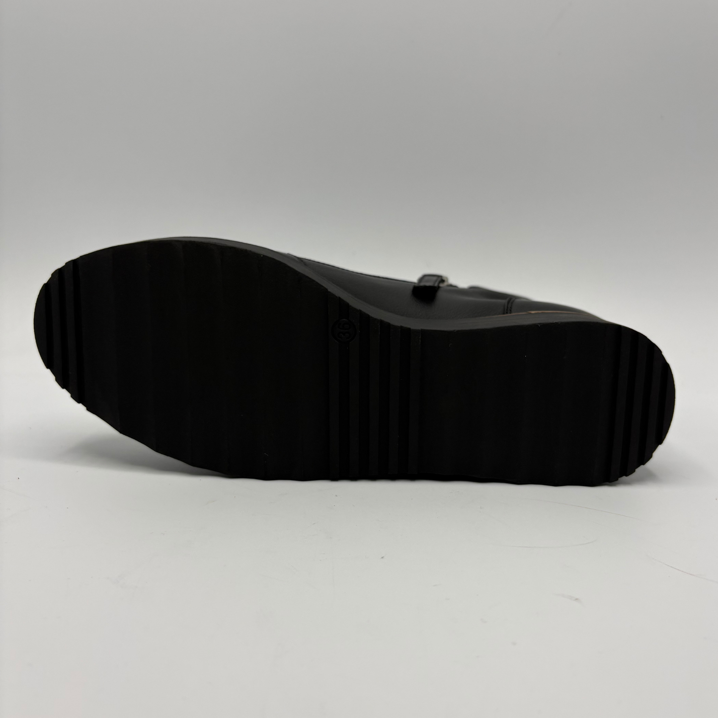 The black rubber sole of a shoe, shown from a top-down view against a light gray studio background.