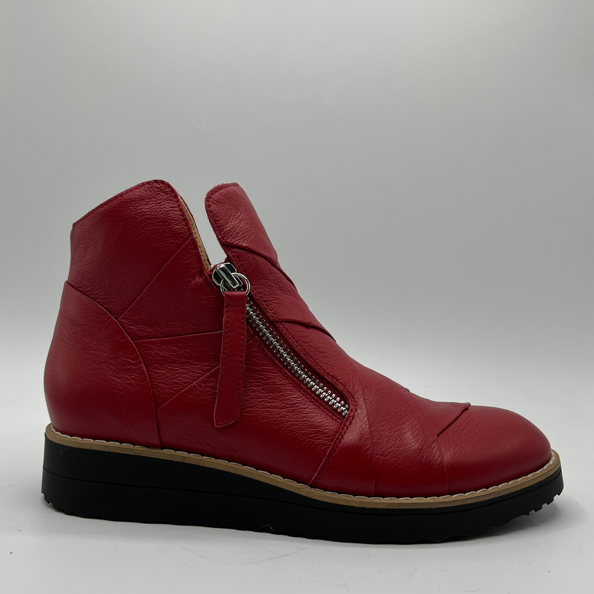 Red leather ankle boot with a zipper on a light gray background