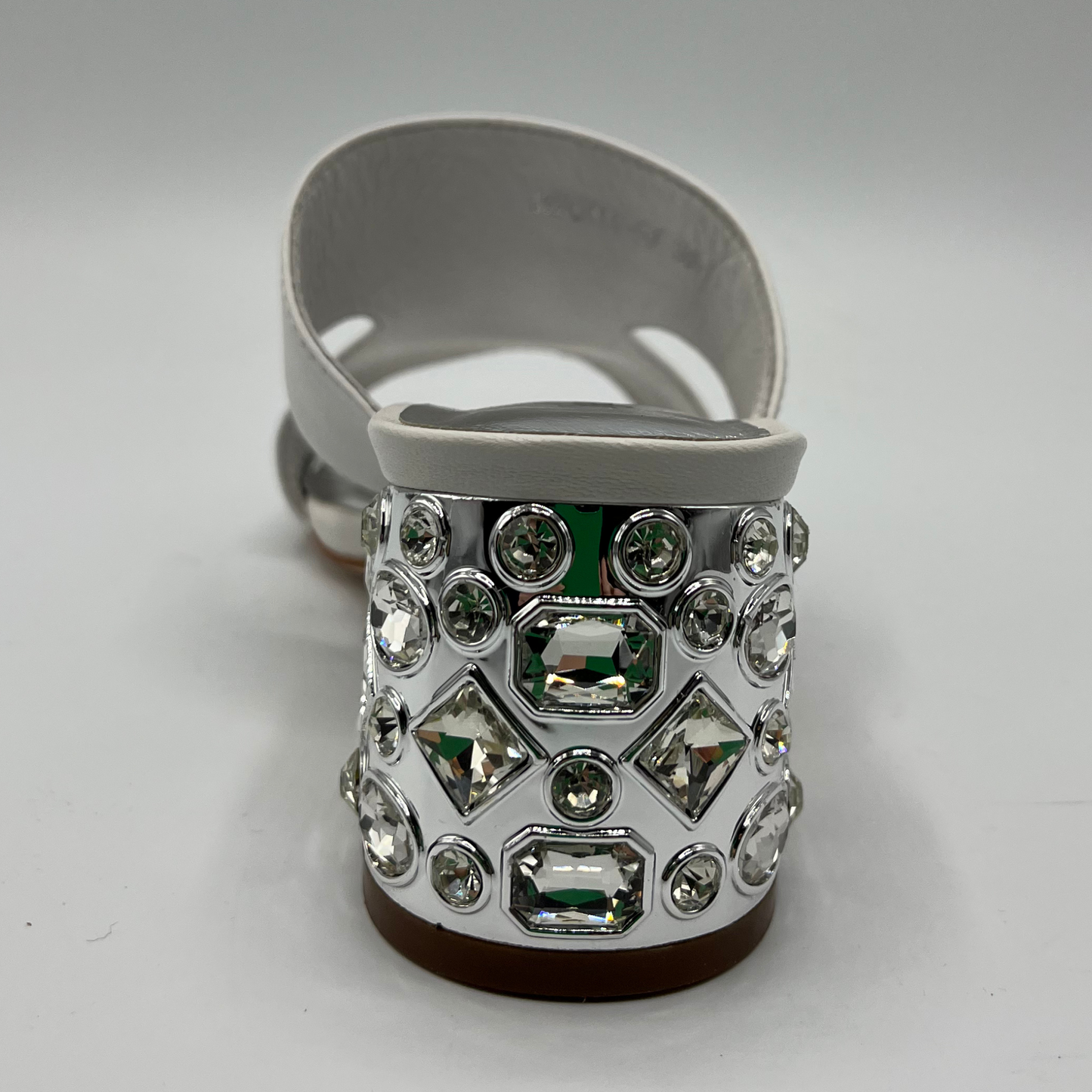Back view of a white leather sandal with a 1/4" bejewelled heel and side cut outs.